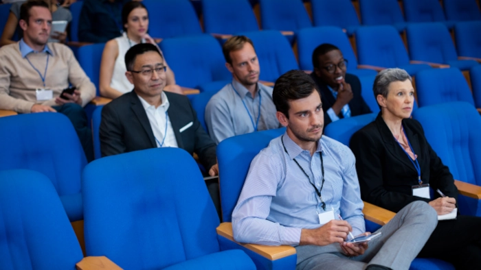 Sept personnes qui assistent à une conférence dans une salle d'amphithéâtre.